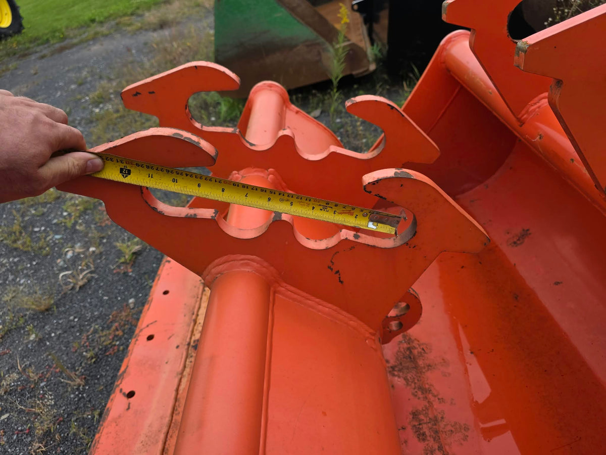 Bucket SSTA 42po dents orange, mesure au ruban de l'écartement entre les godets à l'avant