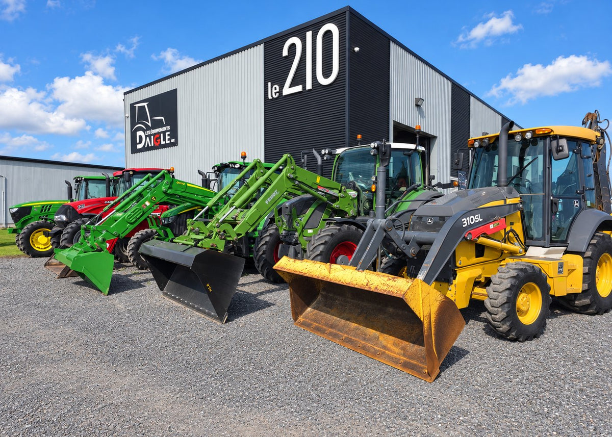 Cour des Équipements Daigle à Issoudun, machinerie agricole et de construction usagée devant le 210
