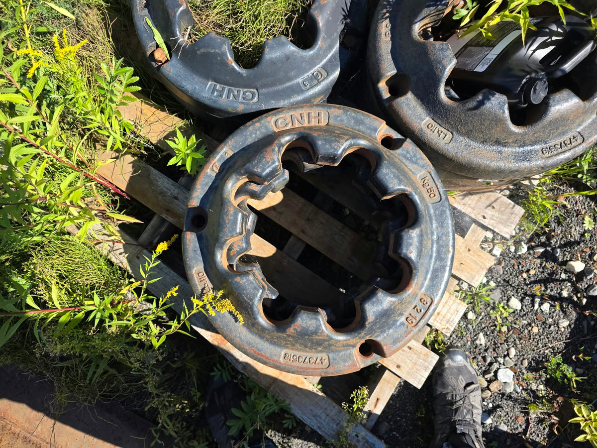 Pesées de roue 50kg New Holland / Case IH, empilées sur palette montrant le marquage CNH