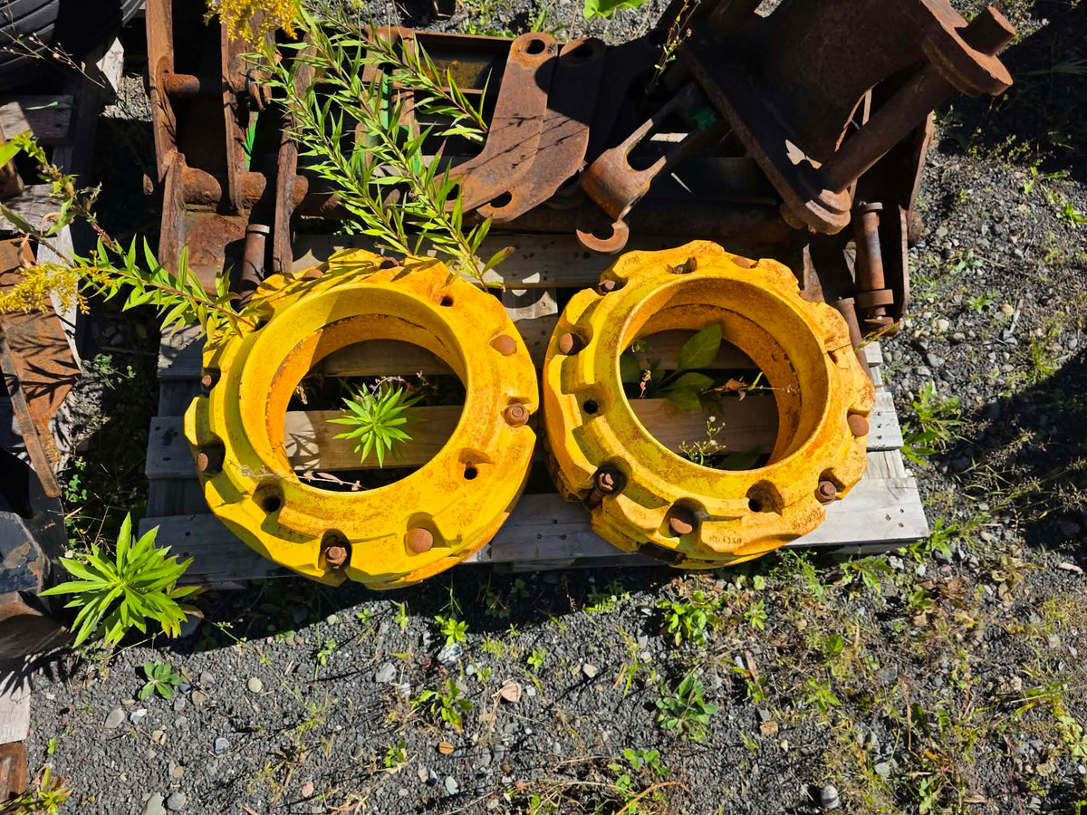 Pesées de roue John Deere 43kg jaunes vue de dessus, deux unités posées sur palette de bois