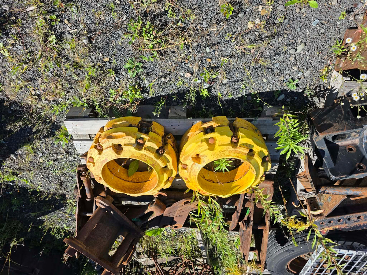 Pesées de roue John Deere 43kg, vue du dessus sur palette de bois, paire jaune entreposée à l'extérieur