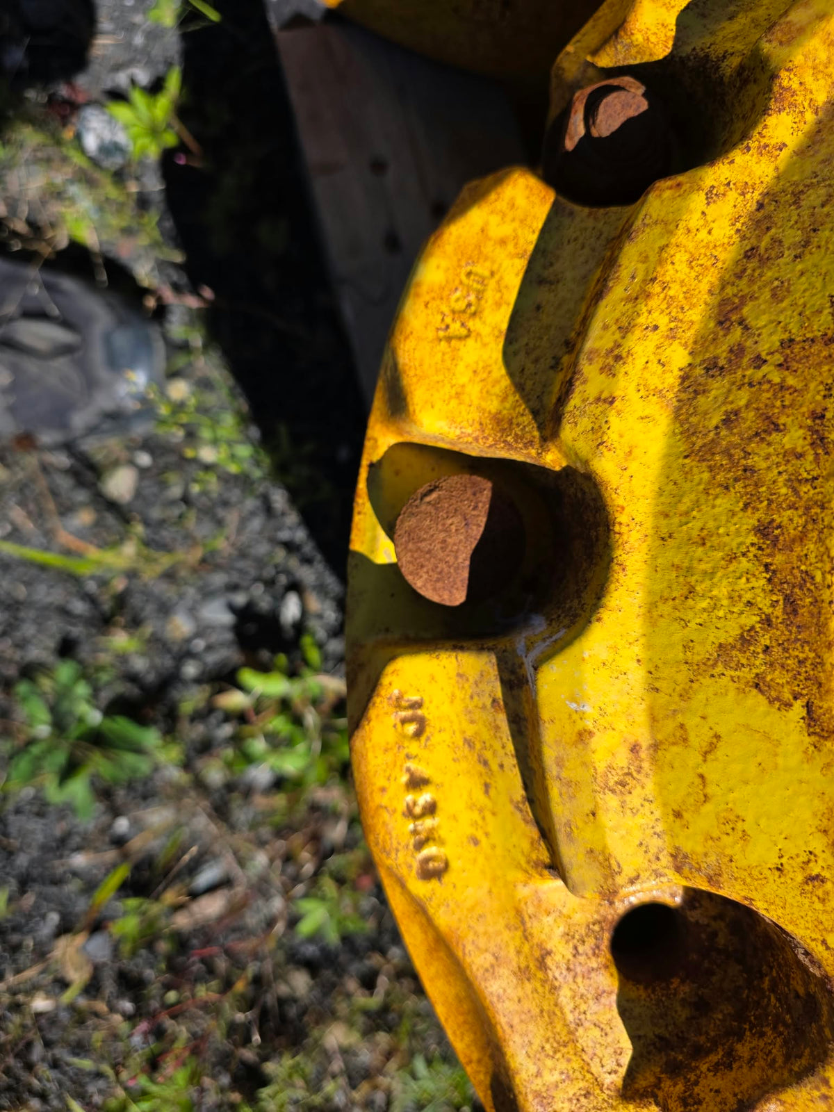 Pesées de roue John Deere 43kg, gros plan sur estampage JD 43KG et rouille visible sur la fonte jaune