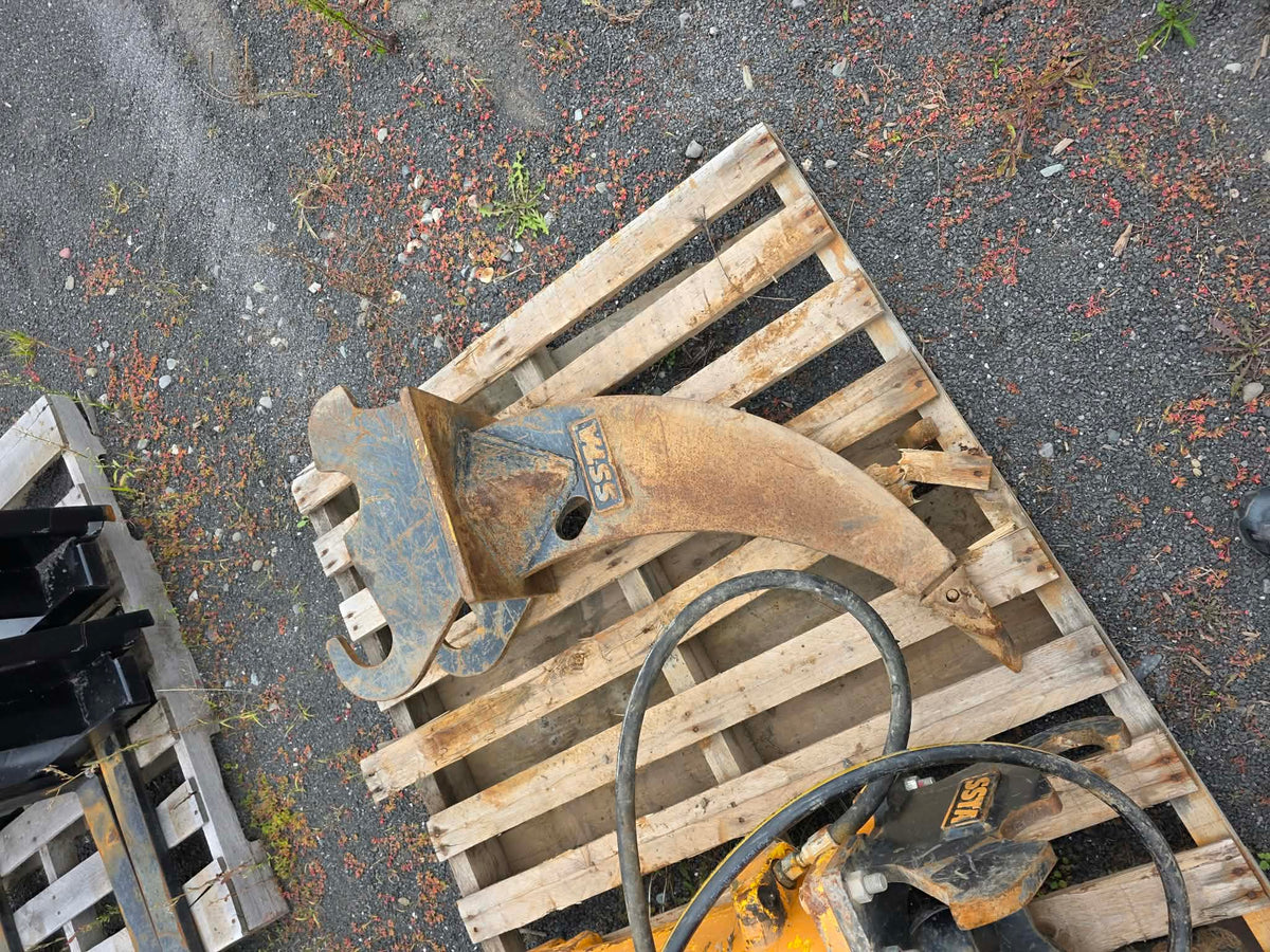 Ripper Ssta pour pelle de 3.5T vue de dessus déposé sur palette de bois, dent et attache visibles