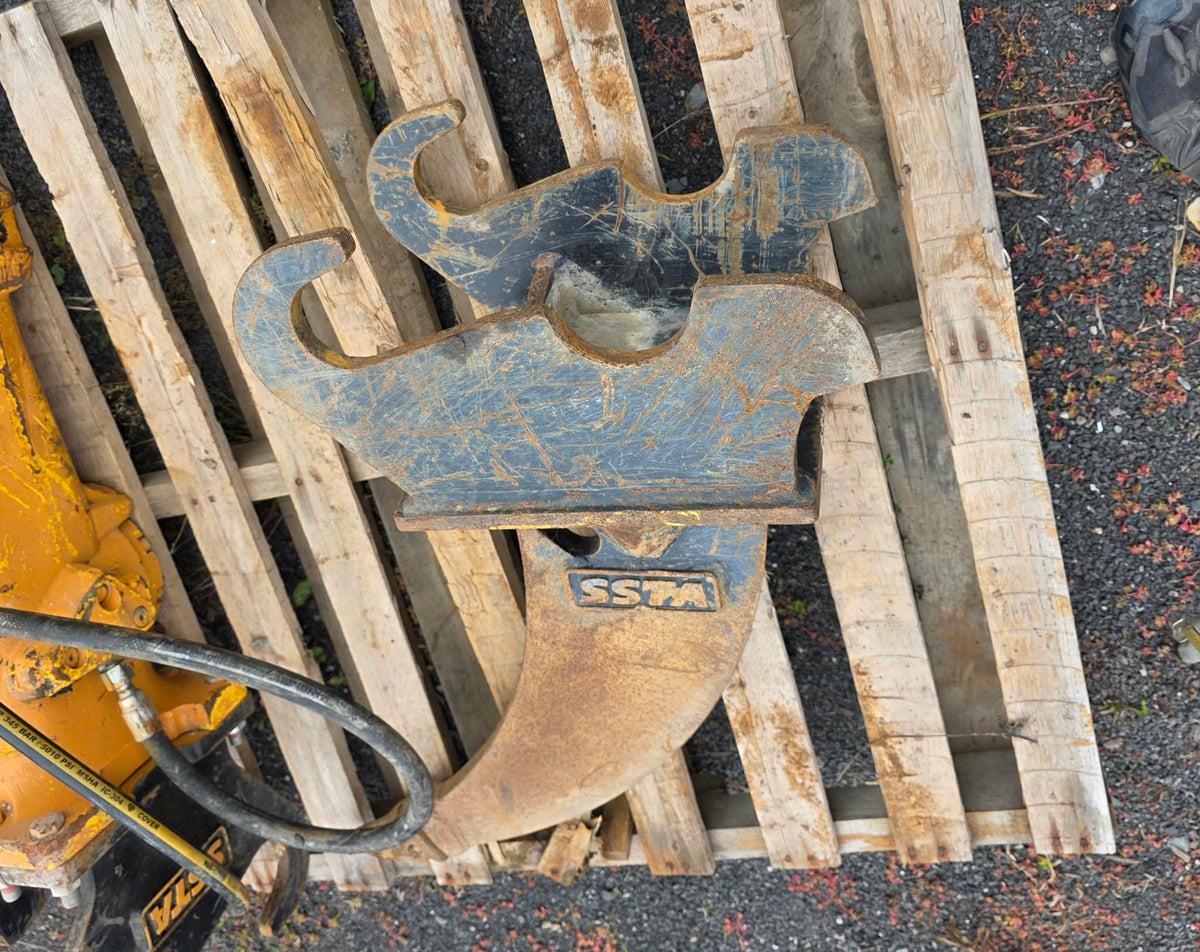 Ripper SSTA pour pelle de 3.5T vu de dessus sur palette, dents et attache usées visibles