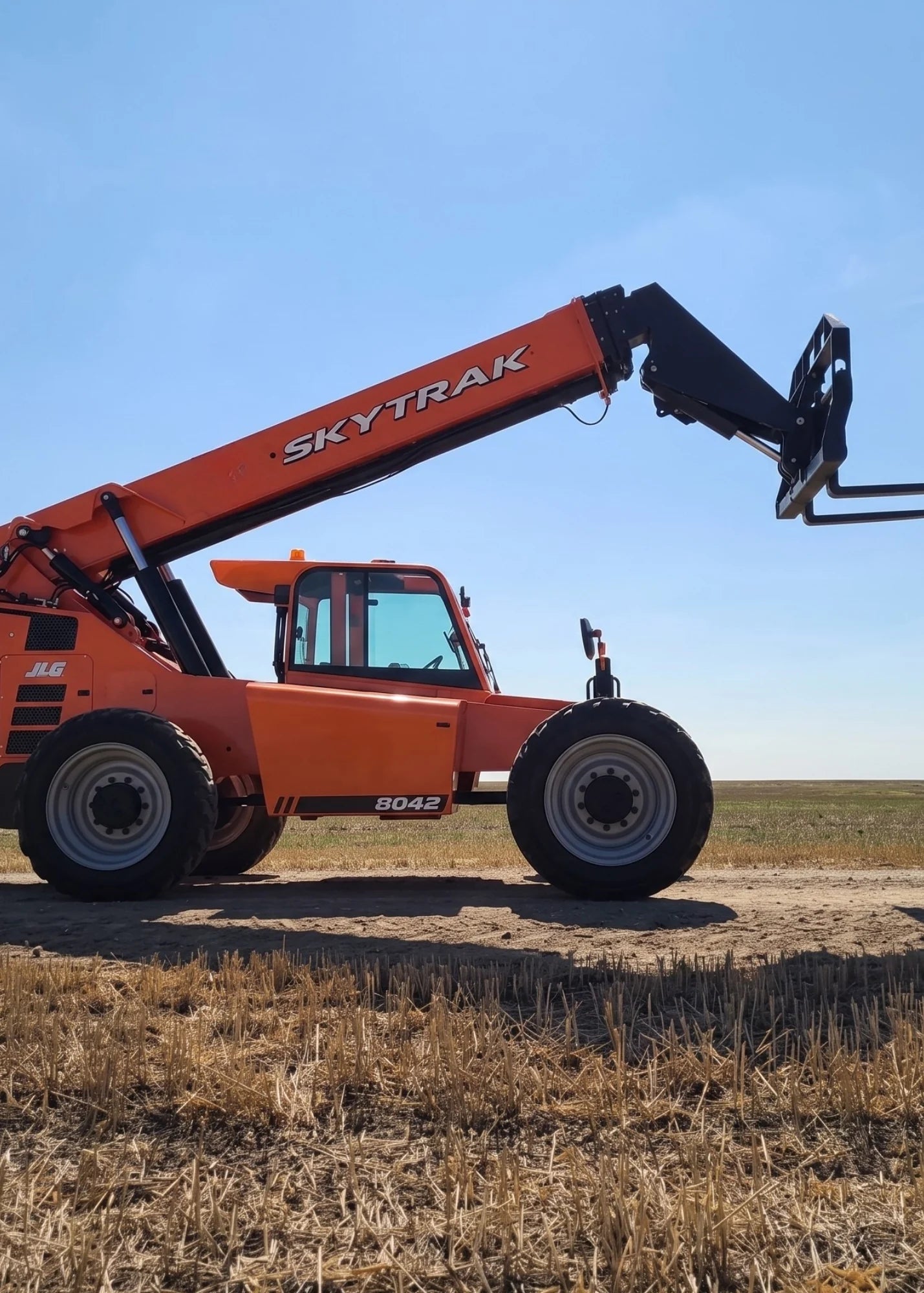 Chargeur télescopique JLG SkyTrak 8042 orange, flèche déployée, dans un champ