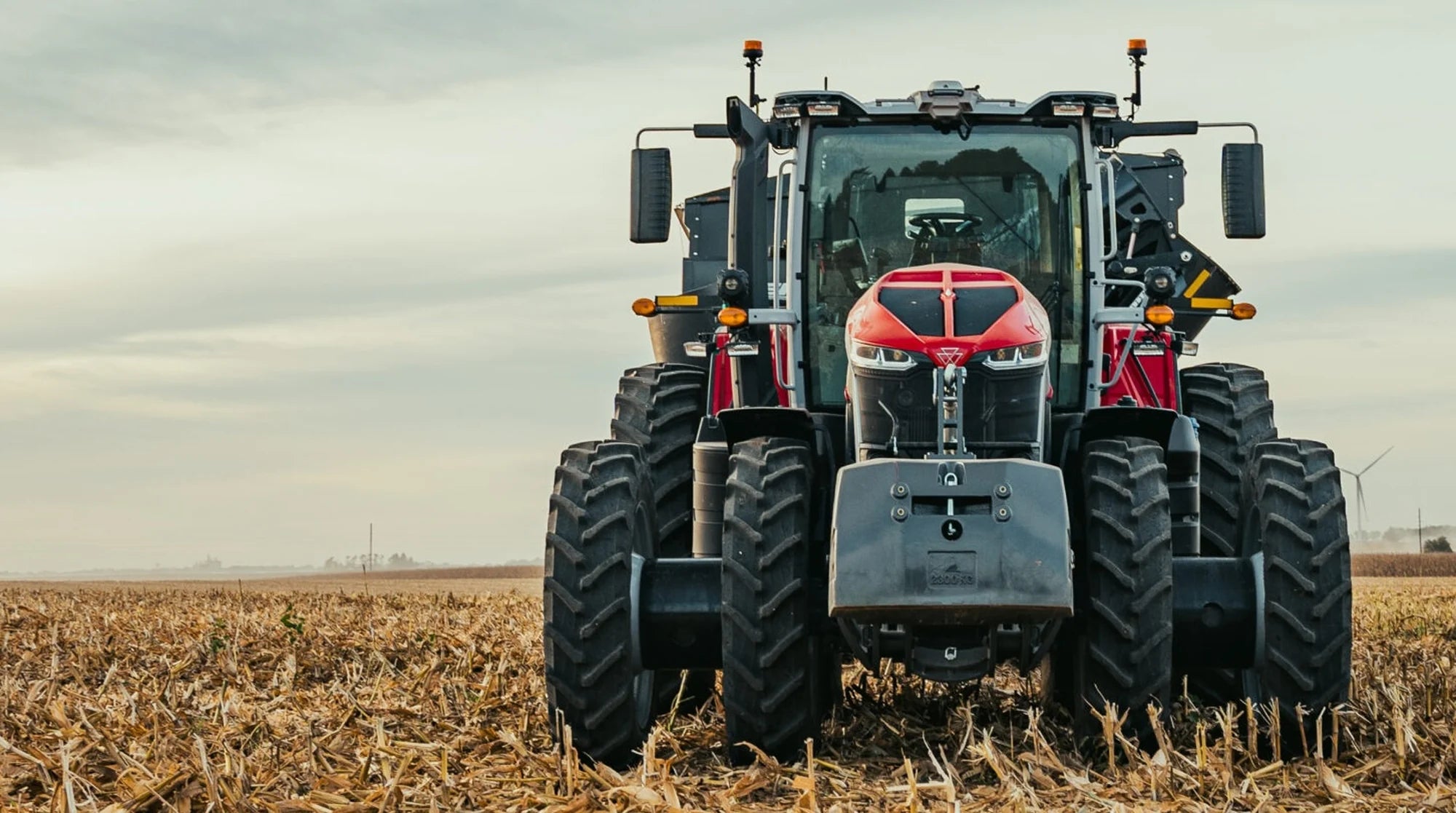 Tracteur Massey Ferguson 9S rouge vu de face dans un champ de maïs récolté