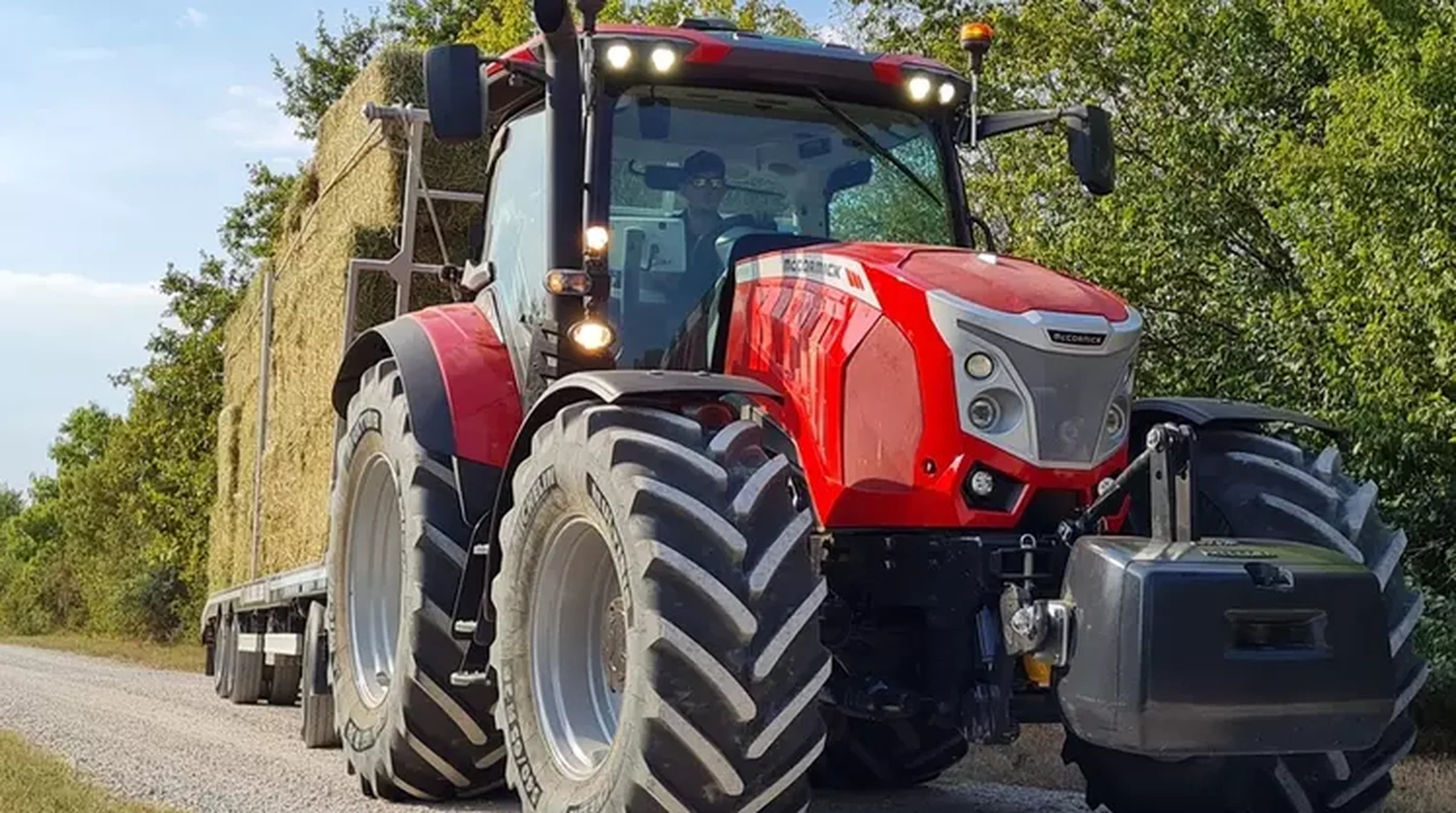 Red McCormick X7 tractor pulling a trailer of hay bales