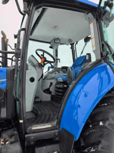 Vue rapprochée du chargeur frontal Stoll installé sur un tracteur New Holland T5.95 usagé, année 2014 avec 3 147 heures. On y distingue les vérins et les raccords hydrauliques robustes, idéals pour la manutention, le déneigement et les travaux agricoles. Tracteur fiable et prêt à travailler, disponible chez Les Équipements Daigle au Québec.
