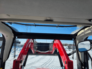 Cab view of Massey Ferguson 4707 looking at raised self-leveling loader