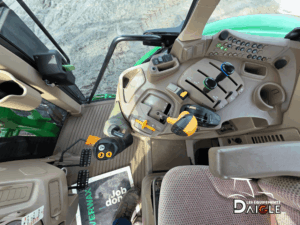 View of the operator station with steering wheel, dashboard, and easy-to-reach controls on the John Deere 6110M.