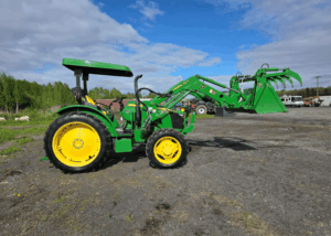 Right-side view of a John Deere 5075E tractor with loader and silage grapple.