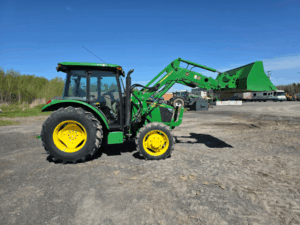 Left side view of the 2019 John Deere 5075E tractor with loader bucket raised.