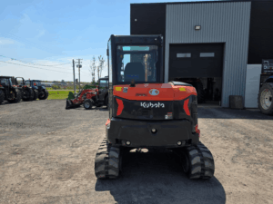 Vue arrière de l'excavatrice Kubota KX057-5 2022 usagée avec cabine fermée et contrepoids intégré