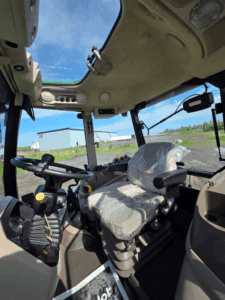 Interior cab view with suspension seat in a 2020 John Deere 5115M tractor.