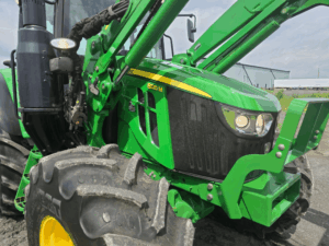 Close-up view of a 2021 John Deere 6120M tractor with front loader
