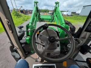 Vue du poste de conduite du John Deere 6120M avec chargeur frontal
