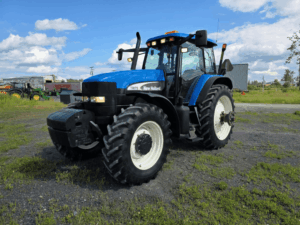 2006 New Holland TM175 tractor with headlights and work lights illuminated.